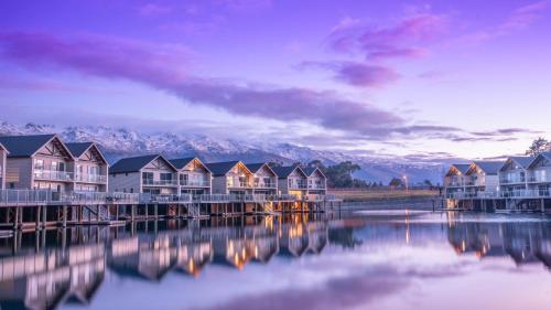 eine Reihe von Häusern auf einem Dock neben einem Wasserkörper in der Unterkunft Marsden Lake Resort Central Otago in Cromwell