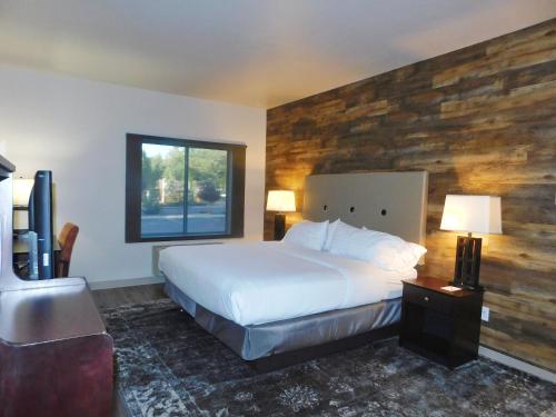 a bedroom with a bed and a wooden wall at GreenTree Inn & Suites Pinetop in Pinetop-Lakeside