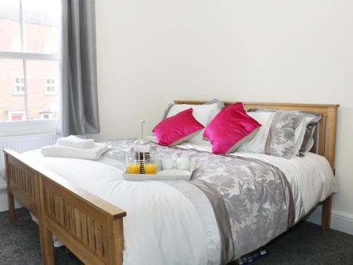 a bedroom with a large bed with pink pillows at 7 Monkmoor Road in Shrewsbury