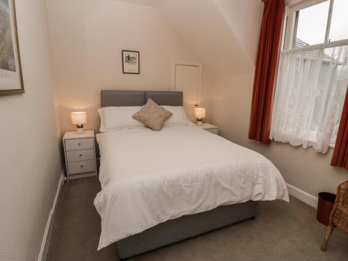 1 dormitorio con 1 cama con 2 mesitas de noche y 2 lámparas en 27-29 St Marys Place en Kirkcudbright