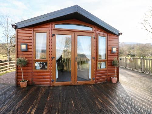 a wooden cabin with glass doors on a deck at The Four Oaks Chalet in Fassfern