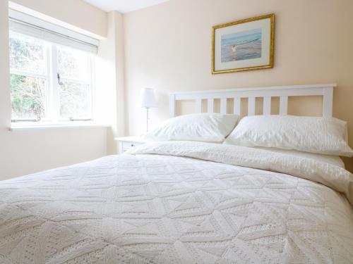 a white bed in a white bedroom with a window at Granary 1 in Hereford