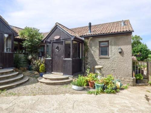 a small house with a wooden door and some plants at The Old Parlour in Winford