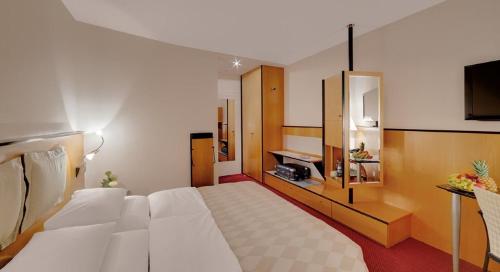 a bedroom with a large white bed and a television at Hotel am Rathaus in Augsburg