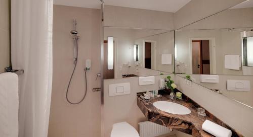 a bathroom with a sink and a large mirror at Hotel am Rathaus in Augsburg