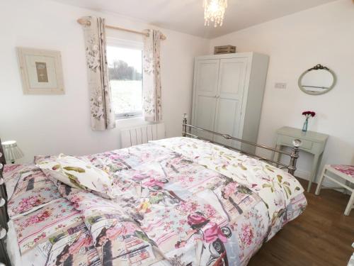 a bedroom with a bed with a floral comforter at The Goose Shed in Thornton