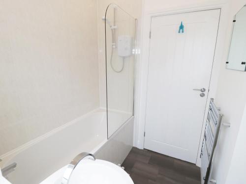 a white bathroom with a shower and a toilet at The Goose Shed in Thornton