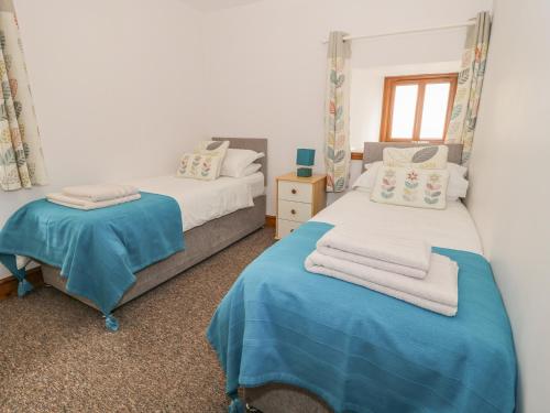 a bedroom with two beds and a table with towels at Wellhope View Cottage in Alston