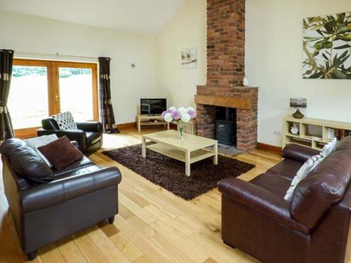 a living room with leather furniture and a fireplace at Parsley Cottage in Conder Green