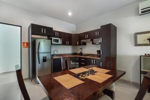 Una cocina con mesa de madera y refrigerador de acero inoxidable. en Villas Akalan, en Tulum
