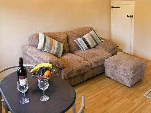 Sala de estar con mesa, botella de vino y sofá en Candy Cottage, en Bradford Abbas
