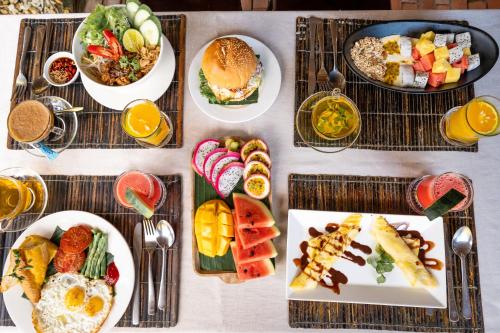 a table topped with plates of food and fruit at An Bang Gold Coast Beach Villa in Hoi An