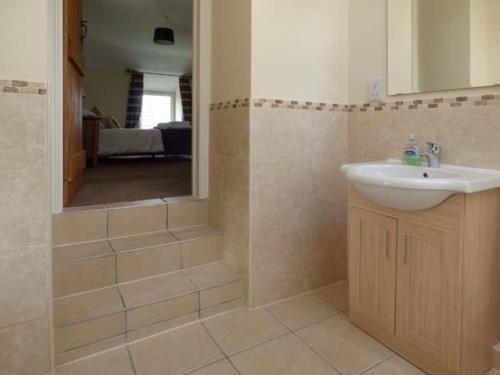 a bathroom with a sink and a shower with a mirror at Penuwch Fach in Llanfihangel-y-creuddyn