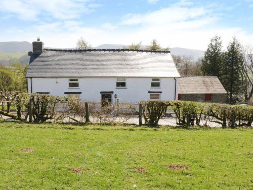 a white house in a field with a fence at Bryndan in Machynlleth