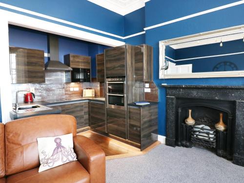 a kitchen with blue walls and a chair and a fireplace at Apartment 3 in Tenby