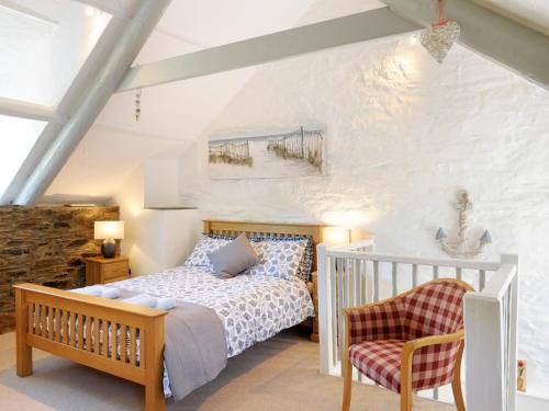 een slaapkamer met een bed en een stoel bij Hele Stone Cottage in Launceston