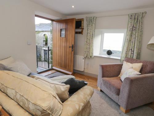ein Wohnzimmer mit einem Sofa, einem Stuhl und einem Fenster in der Unterkunft The Granary Loft in Sunbrick