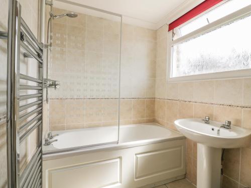 a bathroom with a tub and a sink at 22 Trembel Road in Helston