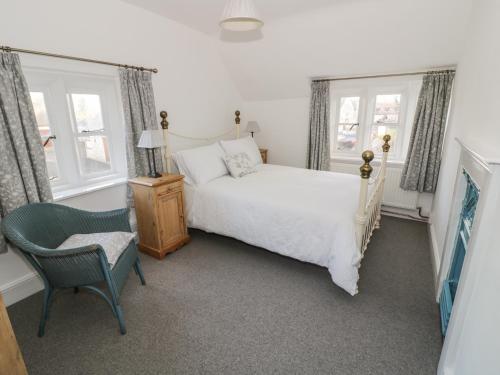 een slaapkamer met een bed, een stoel en ramen bij Bear's Cottage in South Littleton