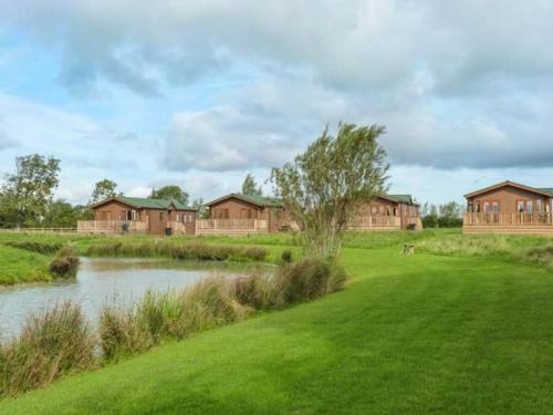 a house in a field next to a pond at Morgan Lodge in Puxton