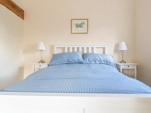 a white bed with blue sheets and two night stands at Granary 2 in Hereford