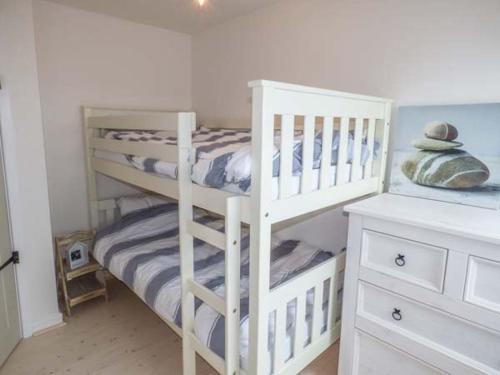 białe łóżko piętrowe w białym pokoju w obiekcie Isallt Lodge w mieście Holyhead