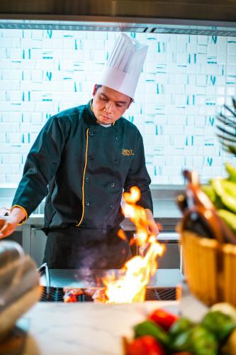a chef cooking food on top of a grill at Luxent Hotel in Manila