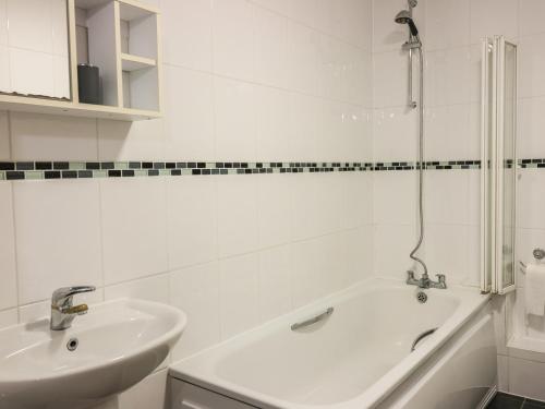 Un baño blanco con lavabo y bañera. en 4 Bredon Court, en Newquay