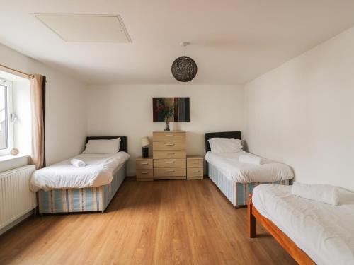 una habitación con 2 camas y un tocador. en 4 Bredon Court, en Newquay