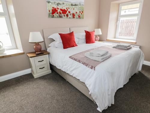 a bedroom with a large white bed with red pillows at Longforth Farm Cottage in Gillespie