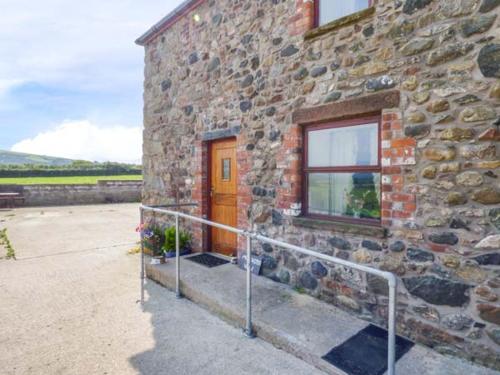 a stone building with a wooden door and a window at Muncaster View in Drigg