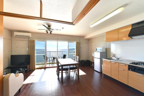 a kitchen with a table and a dining room at Churaumi on the Beach Motobu in Motobu