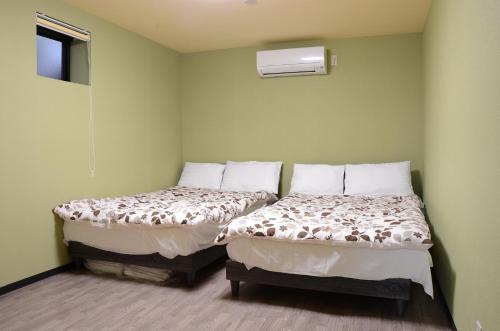 別府市にあるUri Houseの緑の壁の部屋にベッドが2つある