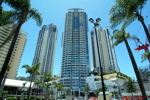 a group of tall buildings in a city with palm trees at Chevron Renaissance managed by Gchs in Gold Coast