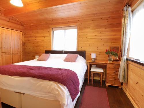 a bedroom with a bed in a wooden cabin at Holly Lodge in Bodmin