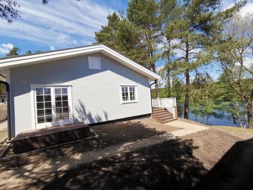 a small white house with trees and a lake at Przystań na Zagórzu - Apartamenty nad jeziorem in Drezdenko