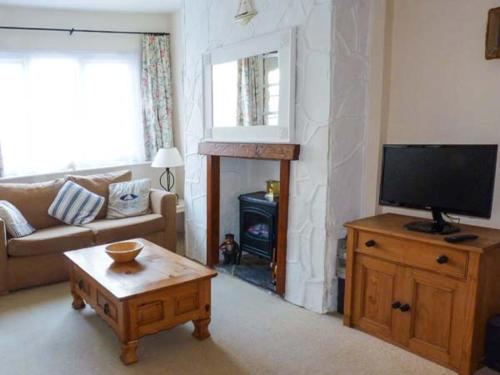 a living room with a tv and a couch and a table at Sunshine Cottage in Teignmouth