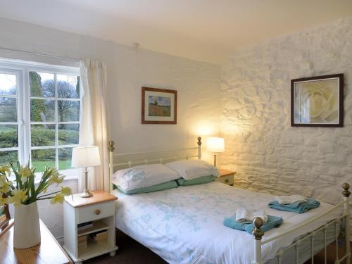 1 dormitorio con 1 cama con 2 lámparas y una ventana en Old Mill Cottage, en Camelford