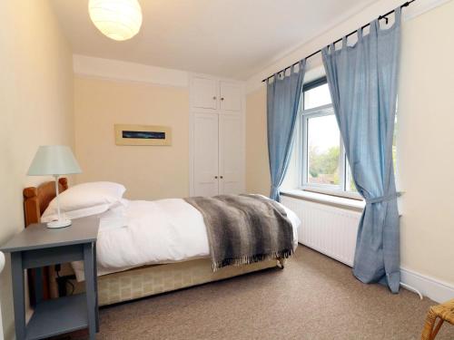 a bedroom with a bed and a window with blue curtains at Whites Meadow in Bicknoller