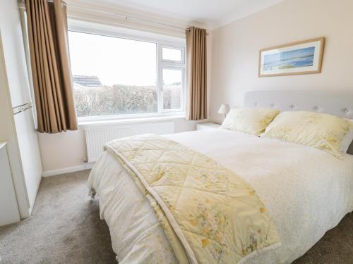 a bedroom with a bed and a large window at Rhos Cottage in Benllech