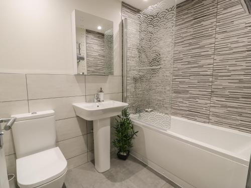 a bathroom with a sink and a toilet and a bath tub at 6 Bay View in Benllech