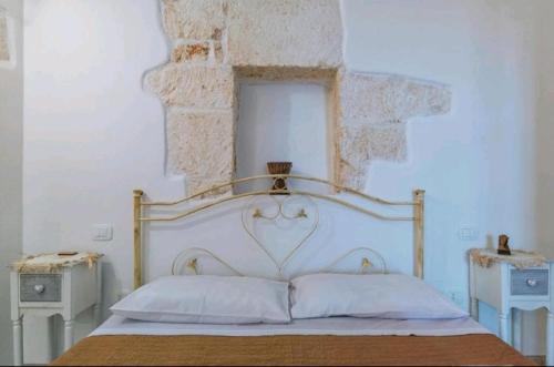 um quarto com uma grande cama branca com almofadas brancas em La perla bianca em Ostuni