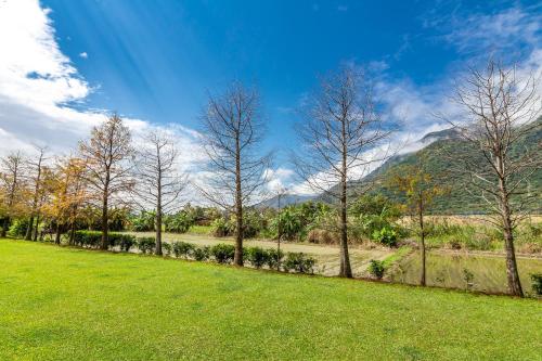 a row of trees in a field with mountains in the background at Simple Life B&B in Jialin