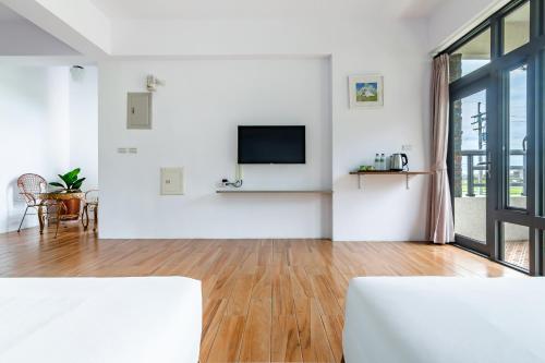 a white living room with a television and a wooden floor at Simple Life B&B in Jialin