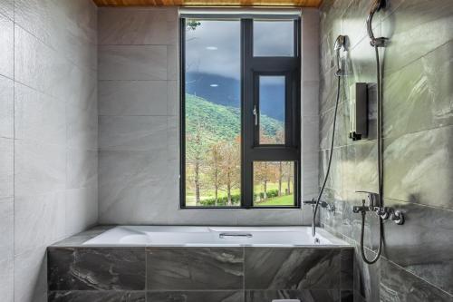 Un baño con bañera y ventana. en Simple Life B&B, en Jialin