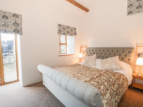 a white bedroom with a large bed and a window at Wern Olau Cottage in Caernarfon