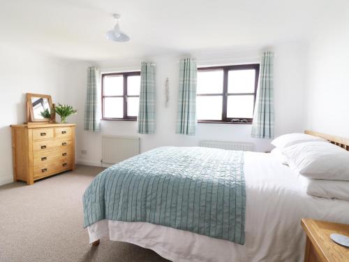 ein Schlafzimmer mit einem Bett, einer Kommode und zwei Fenstern in der Unterkunft Seal Cottage in Woolacombe