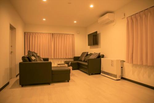 a living room with two couches and a television at SORA 1 in Furano