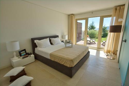 a bedroom with a bed and a large window at Troia Residence by The Editory - Apartamentos Praia in Troia