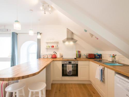 a kitchen with white cabinets and a wooden counter top at Spiral View in Perranporth